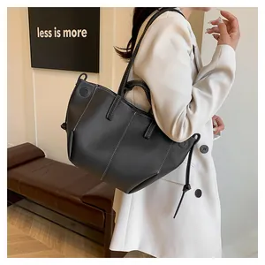 Détail du cabas noir en cuir grainé avec coutures blanches et bandoulière longue