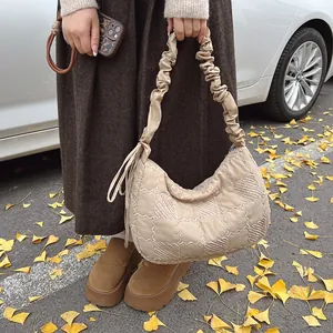 Detail of beige quilted dumpling bag featuring a ruched strap and checkerboard pattern