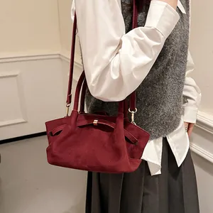 Model wearing a vintage burgundy suede tote bag with elegant gold buckle and long strap