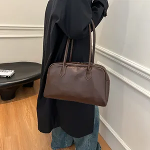 Detailed close-up of glossy dark brown tote bag with vintage texture and long shoulder straps