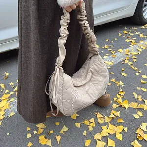 Detail view of beige quilted crescent bag with ruffled straps in autumn outdoor setting