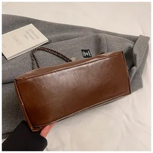 Detail view of the rectangular bottom and oily leather texture of the brown tote bag
