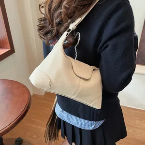 Gros plan sur un sac hobo beige en cuir grainé porté par un mannequin