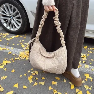 Detail shot of beige quilted dumpling bag with ruched handle in an autumn setting