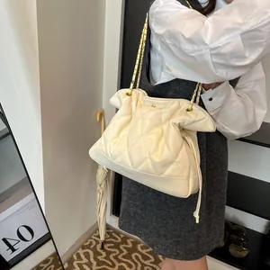 Close-up of cream quilted leather bucket bag with gold chain strap and drawstring closure