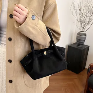 Detail of black faux suede tote bag with golden buckle and sleek aesthetic texture