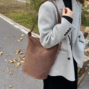 Detail of dark brown suede bucket bag texture and adjustable strap on a shoulder bag