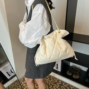 Detail of cream quilted lattice bucket bag showing the golden chain strap and hobo style