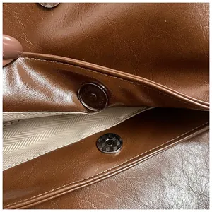 Detail view of the magnetic closure and herringbone fabric lining inside the brown tote bag