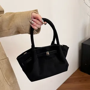 Close-up of black matte suede tote bag with a gold metal buckle and decorative strap
