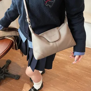 Détail du sac à bandoulière en cuir grainé beige avec texte embossé et coutures soignées