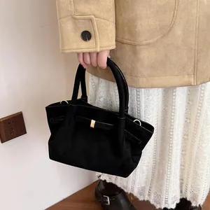 Detail of black suede tote bag with golden metal buckle and vintage leather strap texture