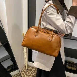 Detail of a brown leather tote bag with soft texture and sturdy shoulder straps