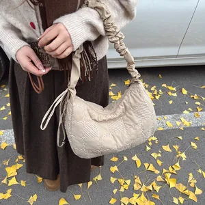 Detail of beige quilted dumpling bag on ginkgo leaves with a ruched shoulder strap