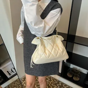 Close-up of quilted cream shoulder bag with golden chain strap and fashion text detail