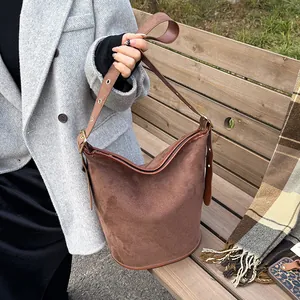 Close-up of a deep brown frosted suede bucket bag with adjustable metal buckle strap