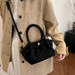 Detail view of black suede tote bag with bow-knot pleats and golden metal hardware