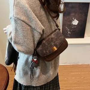 Detail einer dunkelbraunen Vintage-Schultertasche mit Krokoprägung und Goldverschluss