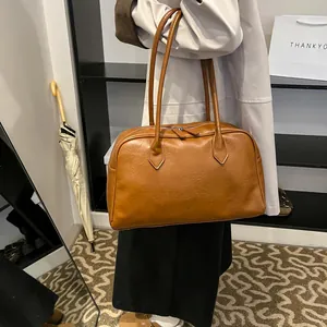 Detail of a brown leather shoulder bag with fine texture and durable metal zipper closure