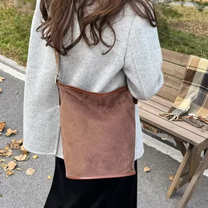 Detail of dark brown suede bucket bag with leather trim against autumn park background