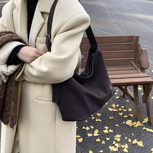Deep brown matte leather tote bag worn by a model in a cozy autumn street setting