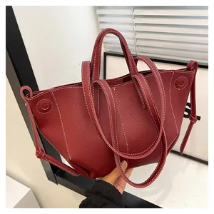 Détail du sac cabas bordeaux en cuir litchi avec surpiqûres blanches et bandoulière