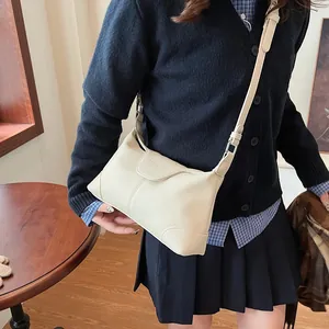Détail d'un sac bandoulière en cuir grainé crème avec bandoulière réglable et rabat fermé