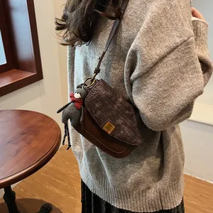 Details der braunen Vintage-Umhängetasche mit Krokodilmuster und Bären-Anhänger