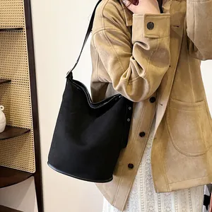 Detail of black suede bucket bag showing silver eyelets and smooth leather shoulder strap