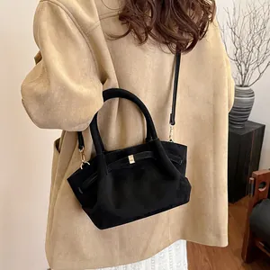 Detail view of vintage black suede tote bag with golden buckle and detachable shoulder strap