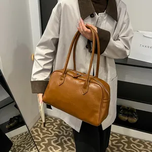 Close-up of caramel brown leather tote bag showing fine stitching and slim shoulder straps