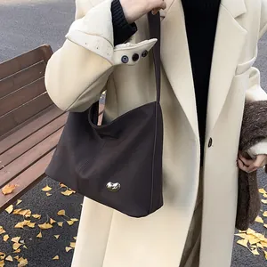 Detail of dark brown leather tote bag with gold bean metal buckle on beige autumn coat