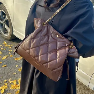Close-up of brown quilted leather bag with gold chain strap and drawstring detail