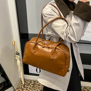 Detail of a brown vintage tote bag showing its glossy faux leather texture and dual zipper