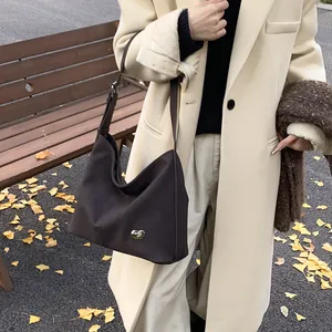 Detail of retro chocolate brown hobo bag featuring a gold metal buckle on a park bench