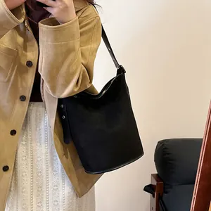 Close-up of black matte suede bucket bag with gold metal eyelets on shoulder strap