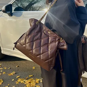 Detail of dark brown quilted chain bag with gold hardware and embossed fashion text