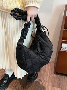 Quilted black puffer dumpling bag with pleated handle and spacious minimalist design