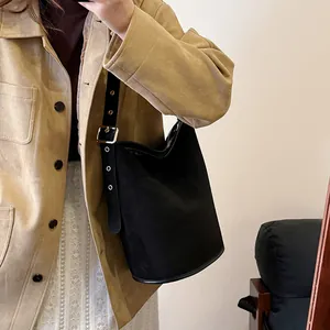 Detail of black matte suede bucket bag with adjustable wide strap and silver metal eyelets