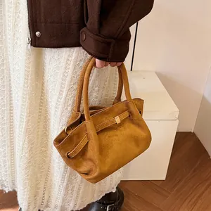 Detail of tan suede tote bag featuring a leather strap with metallic square buckle