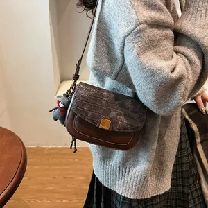 Detail der braunen Vintage-Umhängetasche mit Krokostruktur und goldenem Logo-Verschluss