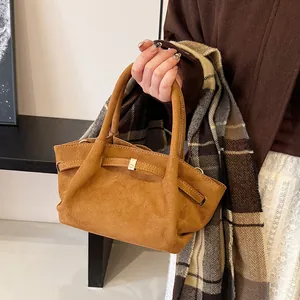 Detail of brown faux suede tote bag featuring elegant golden buckle and round handles