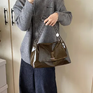 Detailed close-up of dark olive green glossy leather tote with chain strap and text detail