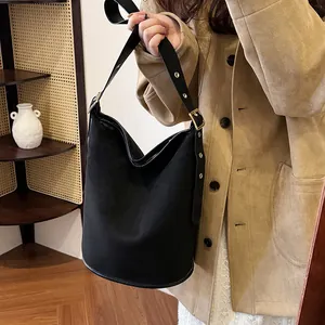 Detail of black matte suede bucket bag with wide strap and golden metal buckle