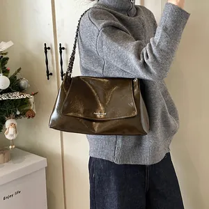 Macro detail of high-shine dark coffee leather tote bag with stylish metal chain strap