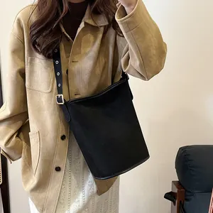 Close-up of matte suede bucket bag with adjustable wide eyelet shoulder strap