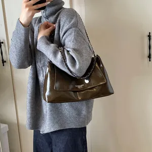 Close-up of dark brown leather tote bag with metal chain strap and logo detail
