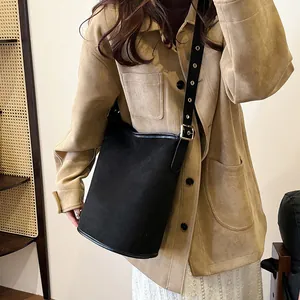 Detail of matte black suede bucket bag featuring leather strap and golden metal buckle