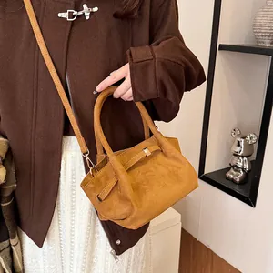 Close-up of caramel suede tote bag featuring silver buckles and adjustable strap