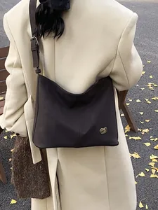 Deep brown matte leather oversized hobo bag on model wearing a white wool coat